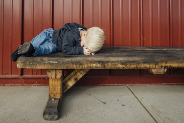 Full length of boy sleeping on wooden bench