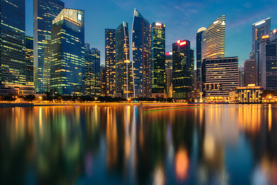 Singapore city skyline. Business district view. Downtown reflected in water at dusk in Marina Bay. Travel cityscape