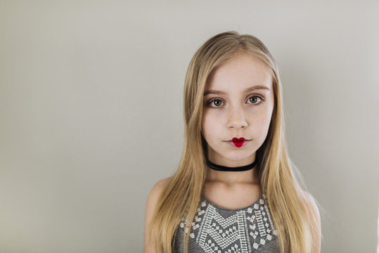 Portrait of girl with heart shape lipstick standing against wall