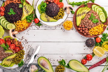 Healthy food. Black rice, buckwheat, avocado, cherry tomatoes, green peas and hazelnut. On a wooden background. Top view. Free space for your text.