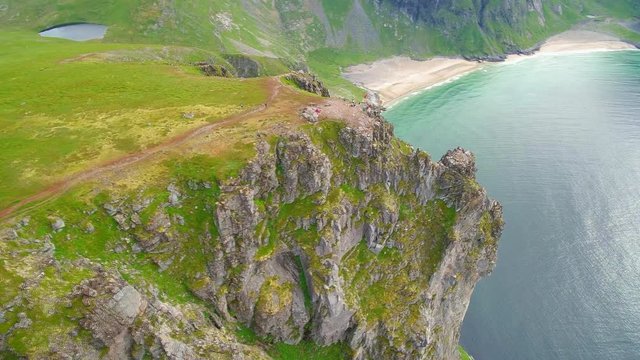 People on cliffs on Lofoten Island, pan right aerial
