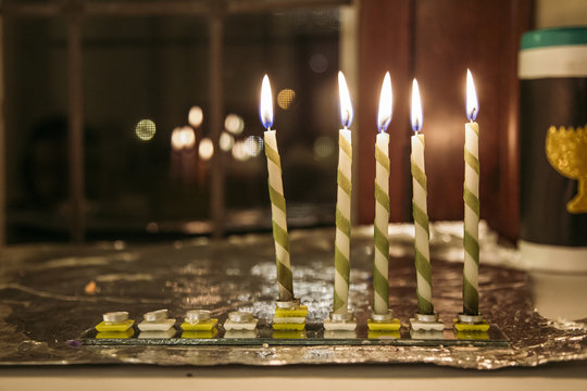 Close-up of illuminated candles on glass at table during Chanukah