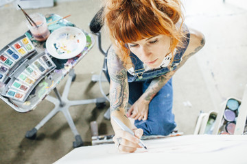 High angle view of artist drawing sketch on canvas in studio
