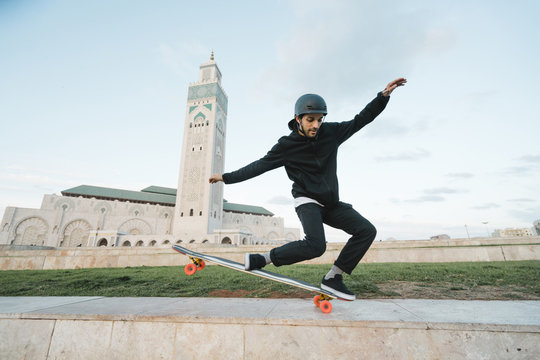 Man performing stunt on skateboard against Hassan II Mosque 