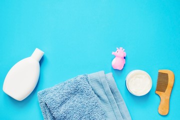 Flat lay bath products on a blue background/ Shampoo bottle, terry towel, pink rubber toy seahorse,...