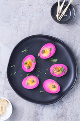 Beet dyed eggs on a black plate. 