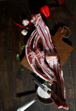 Raw rack of lamb with spices on a cutting board on a dark background