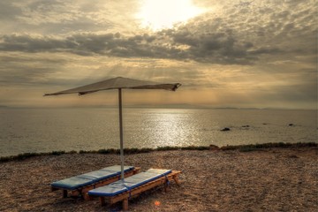 Silhouette of sunbed and beach umbrella on the beach with sunrise background