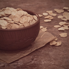 Multi-cereal organic flakes in a brown bowl.