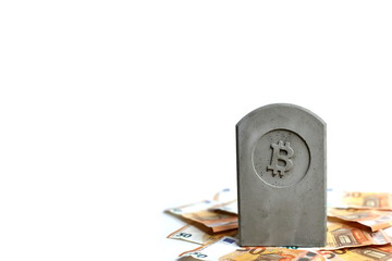 stone monument/tombstone with bitcoin symbol on a pile of banknotes on white background - copy space for text on left side