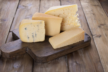 different cheese classic choice, on an old wooden board, cheese knife and cloth
