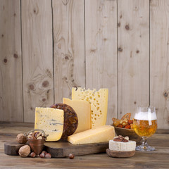 different cheese classic choice, on an old wooden board, nuts and a glass of beer