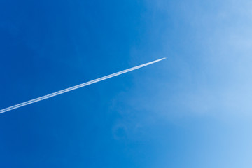 Aeroplane against blue sky and white vapour trail