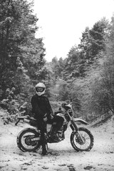 Rider man on a motorcycle Winter motocross. snowy forest. the snow from under the wheels of a motorcycle Enduro. off road dual sport travel tour, active life style concept vertical black and white