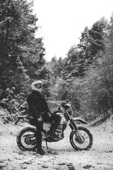 Rider man on a motorcycle Winter motocross. snowy forest. the snow from under the wheels of a motorcycle Enduro. off road dual sport travel tour, active life style concept vertical black and white