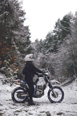 Fototapeta premium Rider man on a motorcycle Winter motocross. Skid on a snowy forest. the snow from under the wheels of a motorcycle Enduro. off road dual sport travel tour, active life style concept vertical