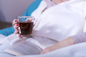 women drink tea and read a book wrapped in blankets