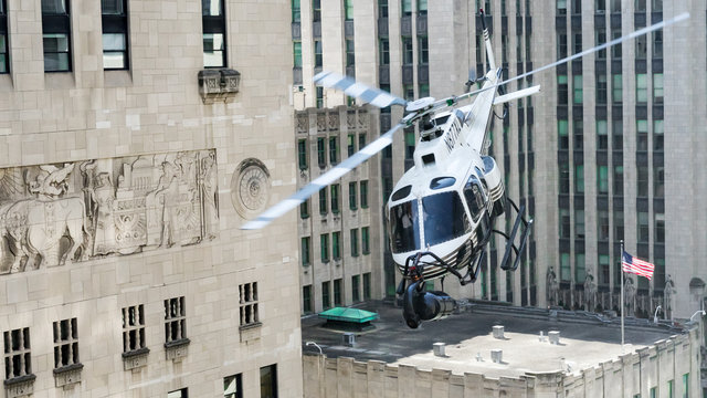Low flying helicopter with large camera on its nose in the middle of Michigan Avenue Chicago