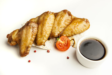 baked chicken wings with sauce and tomatoes on white background