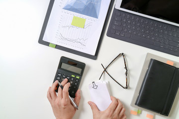 top view of businessman hand working with finances about cost and calculator and latop with mobile phone on withe desk in modern office