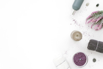 Spa composition on white background. Lilac sea salt, grey candle, towel, lavender flowers. Flat lat, top view