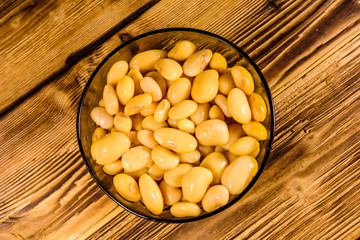White marinated haricot beans in glass bowl on a wooden table. Top view