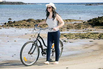 Fototapeta na wymiar Young woman with bike on seaside