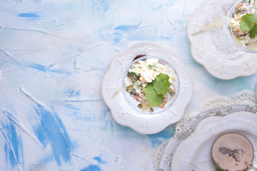 traditional New Year's Russian salad of vegetables and meat, with mayonnaise. Served in a glass and decorated with parsley, on a white table