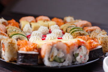 Sushi restaurant menu, Japanese food, delicious seafood concept. Great delicious set of tasty colorful sushi rolls served on the plate with soy sauce and chopsticks, close up, selective focus