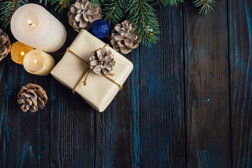 Christmas and Christmas decorations Pine branches of a tree, cones, blue Christmas toys on a wooden background.primary packaging and candles