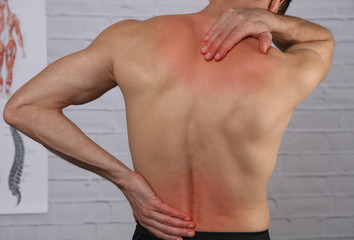 Muscular Man suffering from back and neck pain. Incorrect sitting posture problems Muscle spasm, rheumatism. Pain relief, Chiropractic concept. Sport exercising injury