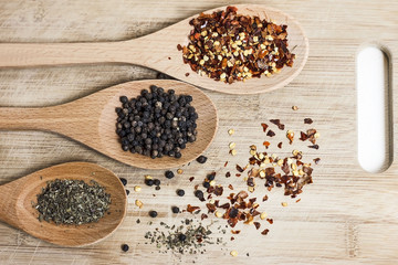 Mixed herbs in wooden spoons. Chilli flakes,  grainy pepper and dried basil.