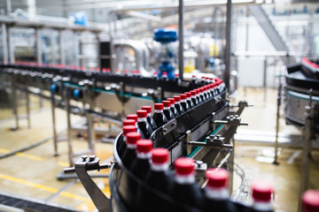 Bottling factory - Black juice bottling line for processing and bottling juice into bottles. Selective focus.  - Powered by Adobe