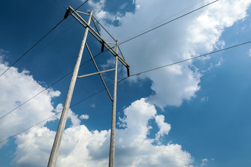 Fototapeta premium High-power electric transmission lines against a blue sky and white clouds