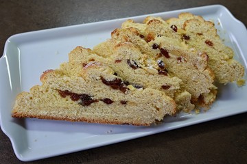 Traditional homemade Czech braided bread freshly baked and sliced on a white ceramic tray with raisins and almonds placed on brown table