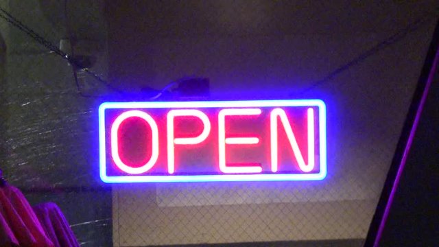 A flashing neon open sign in a window
