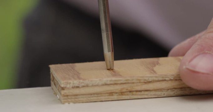 Scratch awl being used to mark point on wood work - extreme close up
