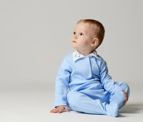 Fototapeta premium Infant child baby boy kid toddler sitting in light blue body cloth looking at the corner