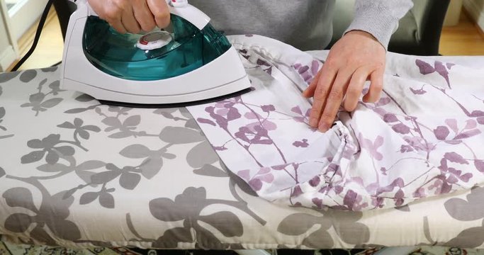 Female hands ironing clothes on iron board 