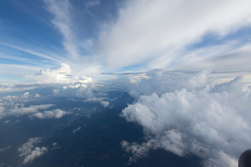 Naklejka na ściany i meble Aerial view on clouds and blue sky from airplane window
