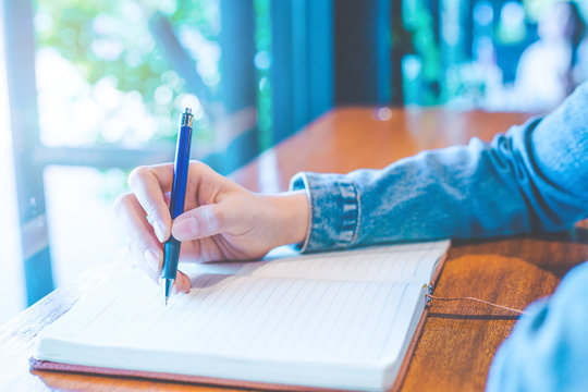 Woman hand is writing on a note pad with a pen in the office.