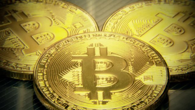 In and out of focus: three physical golden bitcoins (digital virtual crypto-currency) on a semi-transparent surface. Macro close-up shot, mojo colors.
