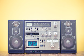 Retro outdated stereo boombox radio cassette recorder circa 1980s front yellow background. Vintage...