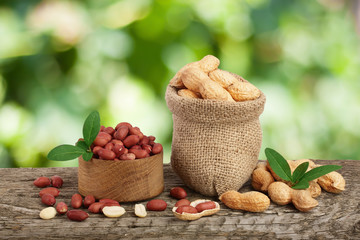 peanuts with leaf in bag on old on wooden table with a blurry garden background