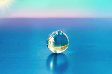 Transparent glass bead closeup on a bright blue cardboard surface, abstract background