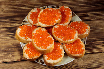 Sandwiches with butter and red caviar on wooden table