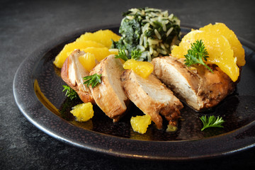 Chicken breast in orange slices with  spinach rice, healthy diet dinner on a dark slate background