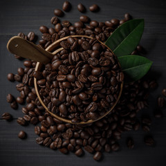 Coffee beans and coffee leaves in the bowl on the wooden table
