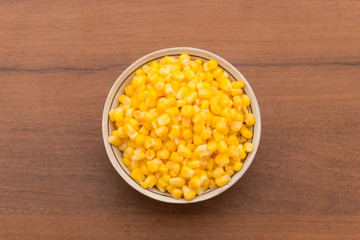 Canned sweet corn in a bowl on wooden table