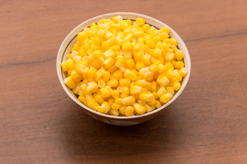 Canned sweet corn in a bowl on wooden table